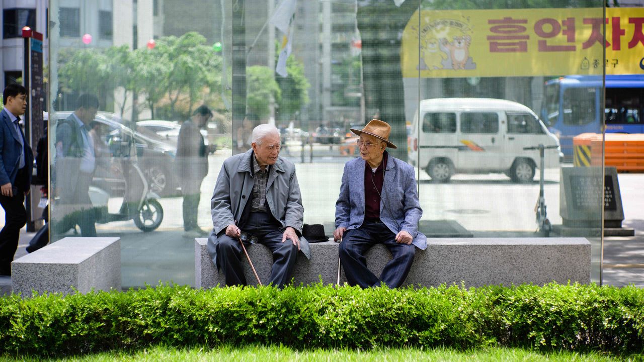 Two elderly men chat on a bench in Seoul, South Korea on May 11, 2023. 