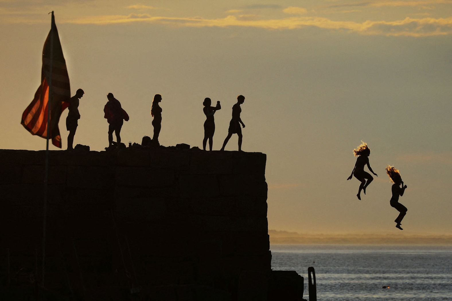 Kids jump into the ocean in Gloucester, Massachusetts, on Monday.