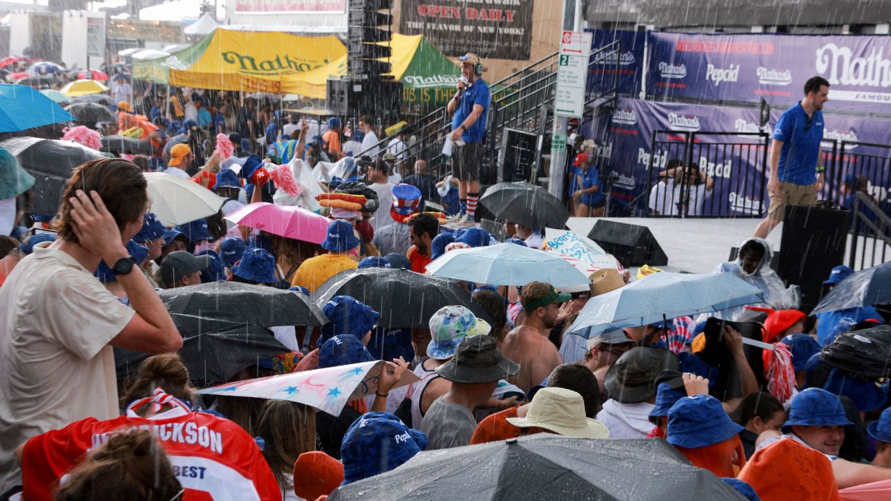 People take shelter from the rain Tuesday at the Nathan's hot dog eating contest.