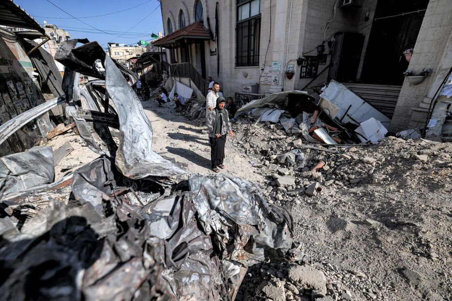 Palestinians are surrounded by rubble and the remains of a destroyed vehicle outside a mosque in Jenin, West Bank, on Wednesday, July 5.