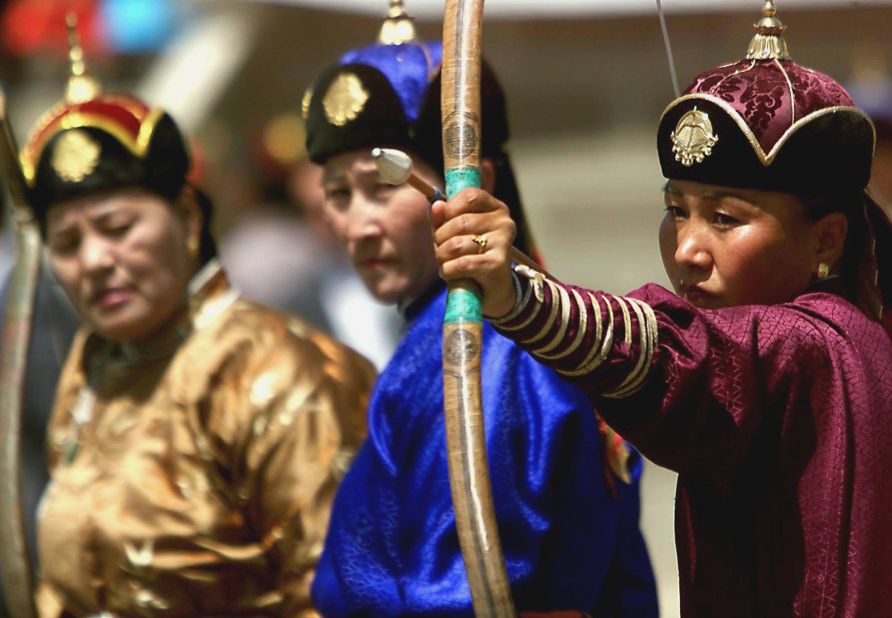 <strong>Skills on display:</strong>  Women dressed in traditional Mongolian clothing compete against each other during Naadam archery matches in the capital. 