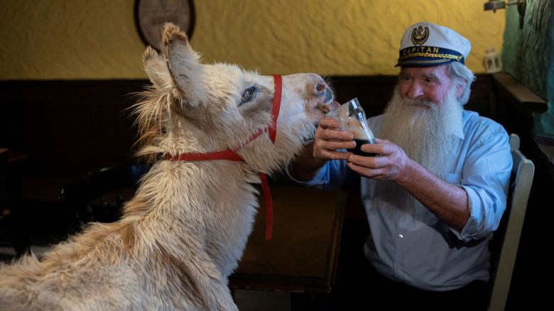 Pake Diskin, 72, holds a glass of Guinness as a donkey called Holly licks it, in the pub that featured in Martin McDonagh's film 'The Banshees of Inisherin' called JJ Devine's Public House, which has been relocated and rebuilt at family-run Mee's Bar, in Kilkerrin, Ireland July 4, 2023. The film pub was built on location on the island of Achill, but was dismantled and left in a yard after the movie wrapped, later salvaged by the Mee family and is now open for business. REUTERS/Clodagh Kilcoyne TPX IMAGES OF THE DAY