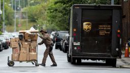 A delivery man pushes a cart full of packages to deliver to an apartment building on an almost empty street in the Shaw neighborhood in Washington, Friday, May 22, 2020. (AP Photo/Andrew Harnik)