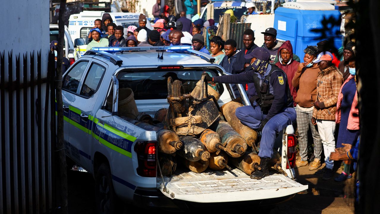 A police officer sits in the back of a police vehicle loaded with illegal mining equipment, after investigating the scene of a suspected gas leak thought to be linked to illegal mining, in the Angelo shack settlement, near Boksburg, east of Johannesburg, South Africa July 6, 2023.