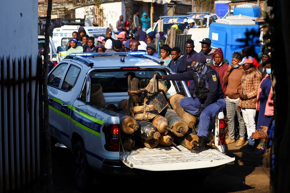 A police officer sits in the back of a police vehicle loaded with illegal mining equipment, after investigating the scene of a suspected gas leak thought to be linked to illegal mining, in the Angelo shack settlement, near Boksburg, east of Johannesburg, South Africa July 6, 2023.