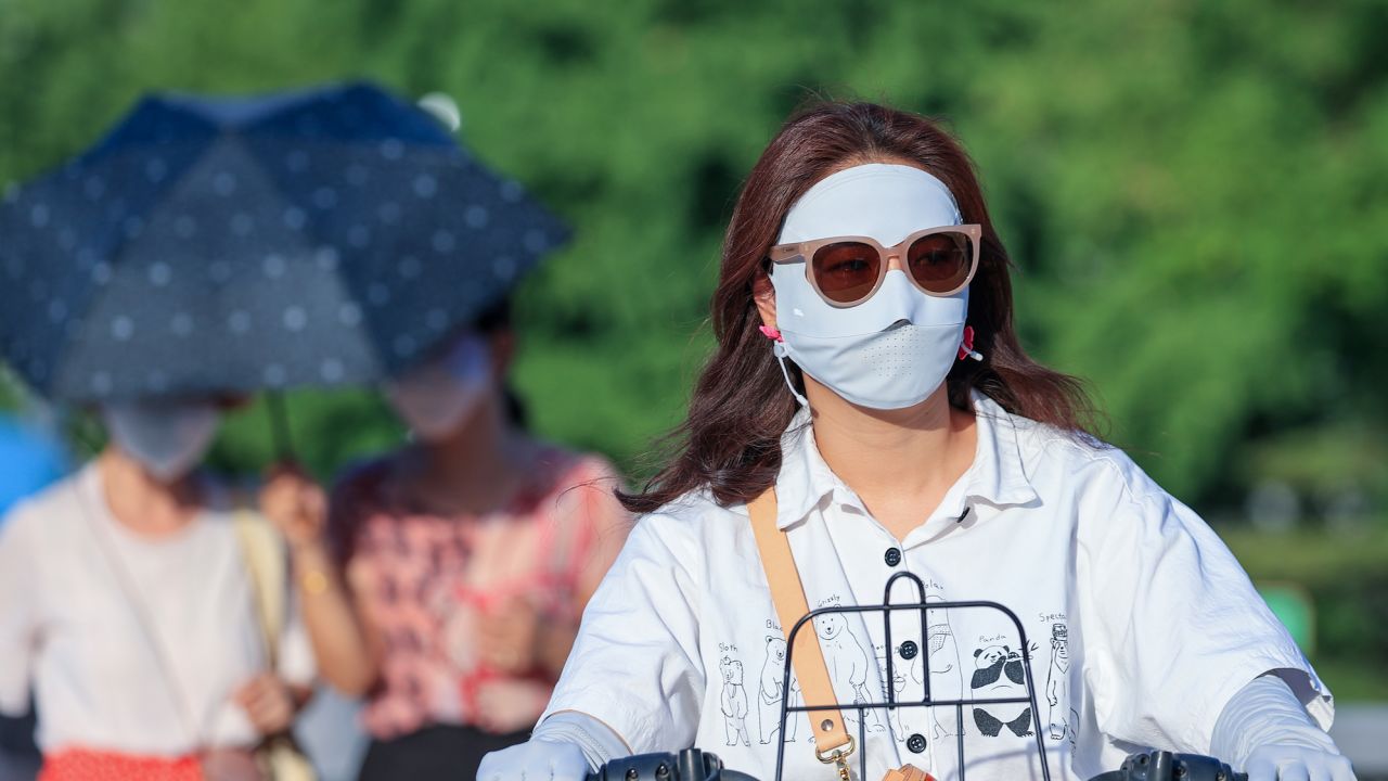 People shield themselves from the sun amid extreme heat on July 5, 2023 in Beijing.