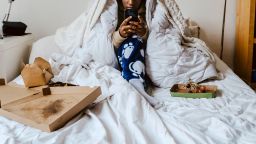 Young woman using smart phone while sitting in bedroom