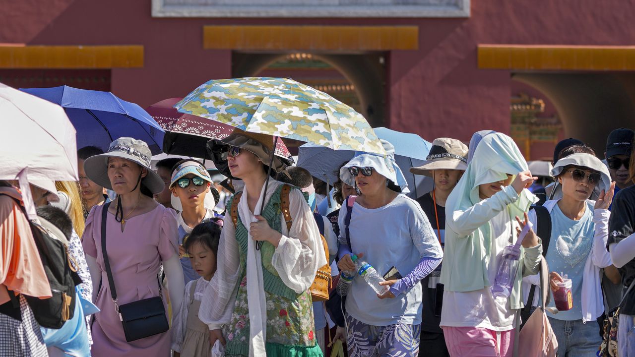 Visitors wear sun hats and carry umbrellas as at the Forbidden City on a hot day in Beijing, on June 29.