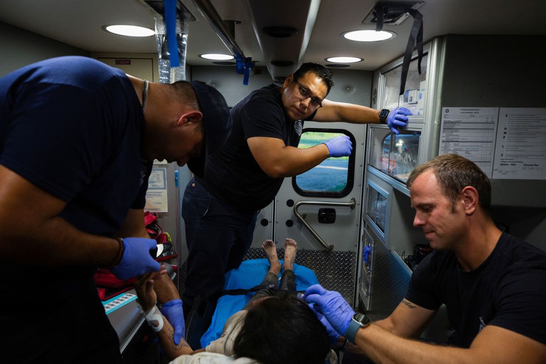 A firefighter EMT team treats a migrant woman suffering from heat exhaustion in the border community of Eagle Pass, Texas, U.S. June 26, 2023. 