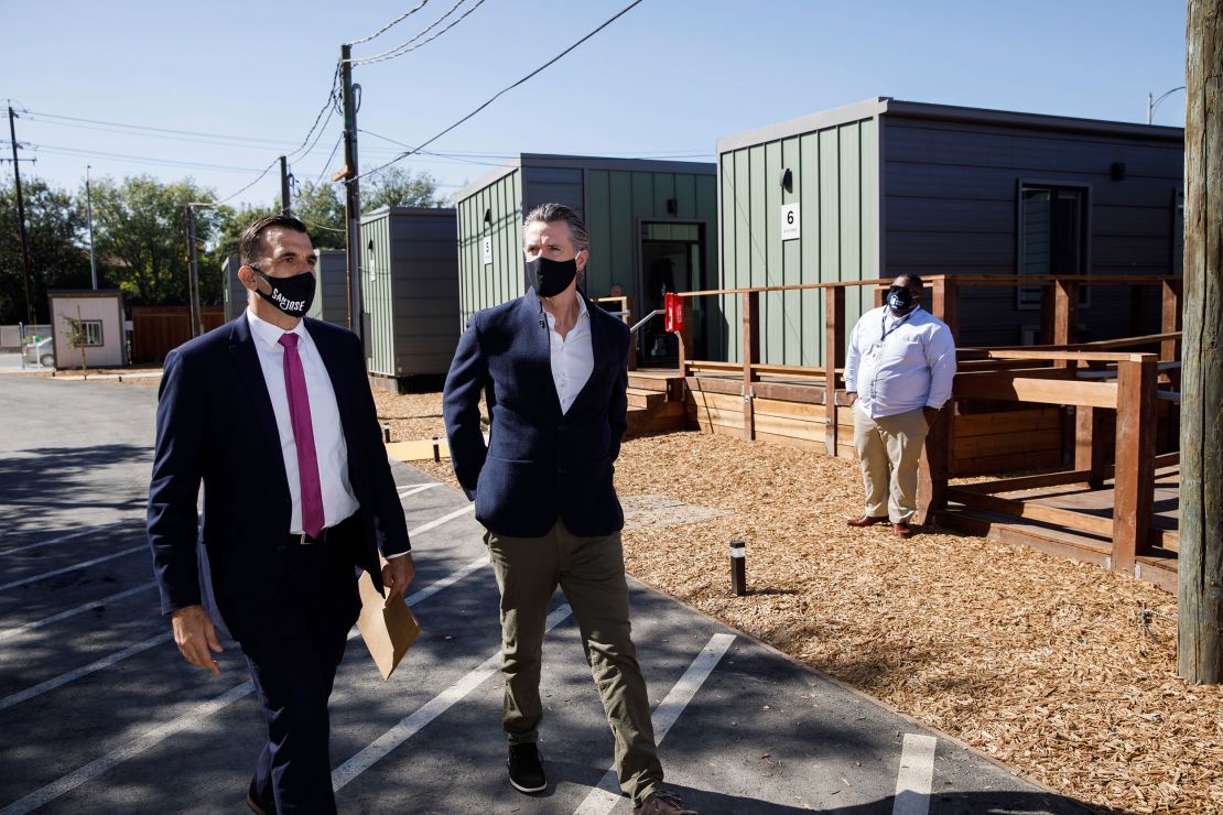 California Gov. Gavin Newsom, center, and San Jose Mayor Sam Liccardo, left, tour an emergency housing community site in San Jose in October 2020, shortly after Newsom announced more funding to fight homelessness.