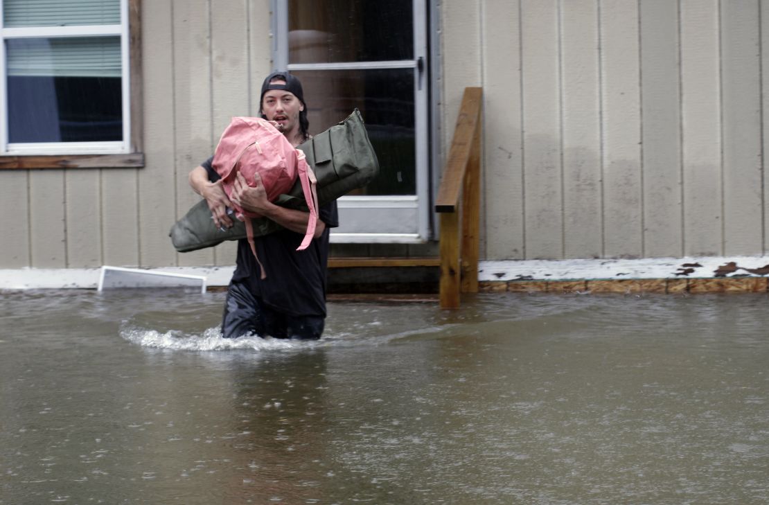 A man carries belongings through floodwaters from a home in Bridgewater, Vermont, on Monday. 