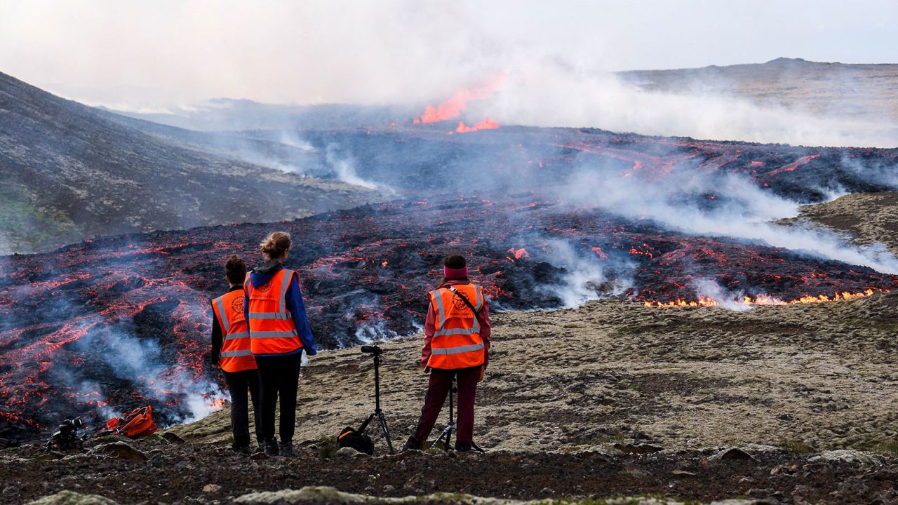 Visitantes da Universidade da Islândia assistem a uma erupção vulcânica perto de Litli Hruður, na Islândia, em 10 de julho de 2023.