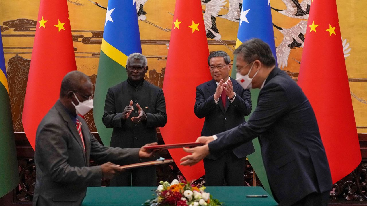 Solomon Islands Prime Minister Manasseh Sogavare and Chinese Premier Li Qiang applaud as both countries' officials exchange signed documents in Beijing on July 10, 2023.