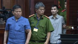 Australian man Chau Van Kham, left, is escorted into a court room in Ho Chi Minh city, Vietnam Monday, Nov. 11, 2019. Kham was sentenced to 12 years in jail for conducting activities of "terrorism to oppose the people's administration." (Nguyen Thanh Chung/VNA via AP)