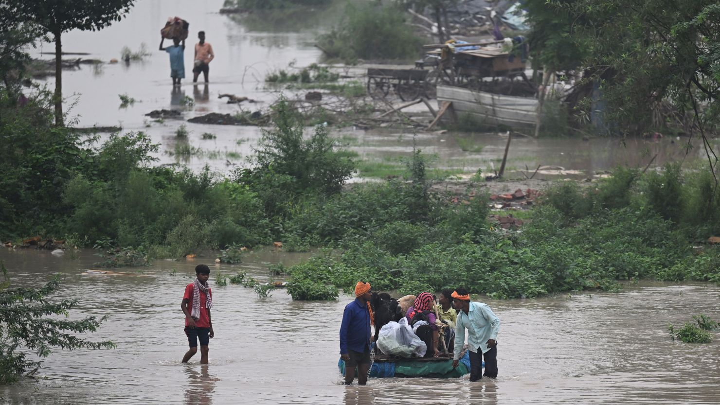 People use a makeshift raft to relocate cattle from a flooded area near the Yamuna River after it overflowed due to monsoon rains in New Delhi on July 11.