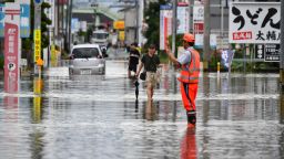 Residents manoeuver through a flooded street in the city of Kurume, Fukuoka prefecture, on July 10, 2023, after heavy rains hit wide areas of Kyushu island. One person died in a landslide and hundreds of thousands of people have been urged to evacuate their homes in southwestern Japan as forecasters on July 10 warned of the "heaviest rain ever" in the region. (Photo by Kazuhiro NOGI / AFP) (Photo by KAZUHIRO NOGI/AFP via Getty Images)