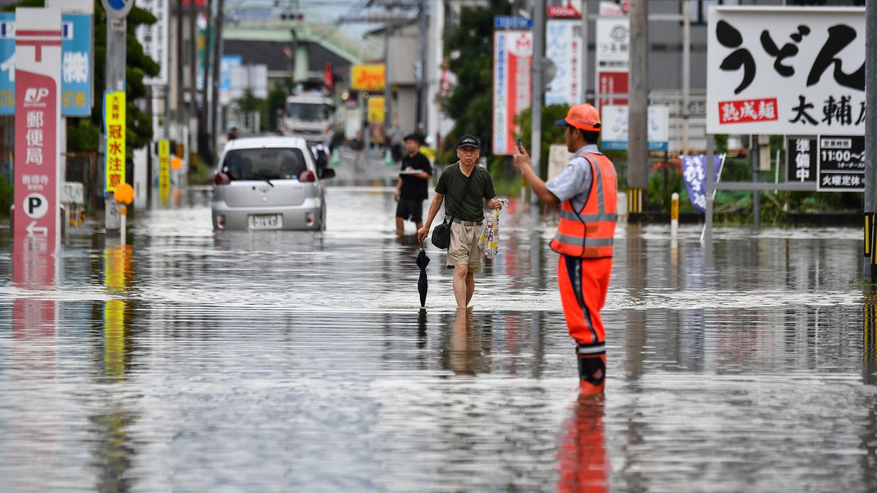 Residents maneuver through a flooded street in the city of Kurume, Fukuoka prefecture, on July 10, 2023.