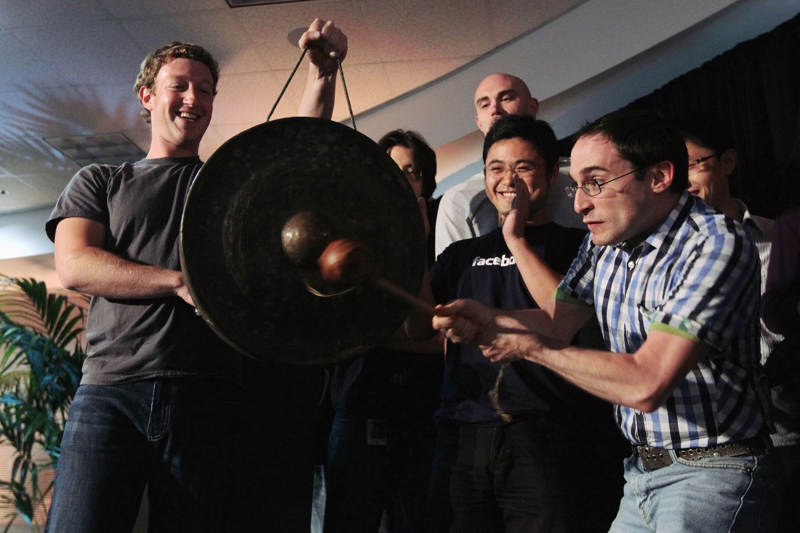 Zuckerberg watches Facebook employee Ben Gertzfield strike a ceremonial gong, used when a new product is launched, during a news conference at Facebook headquarters in August 2010. Zuckerberg was announcing the launch of Facebook Places, an application that allows Facebook users to document places they have visited.