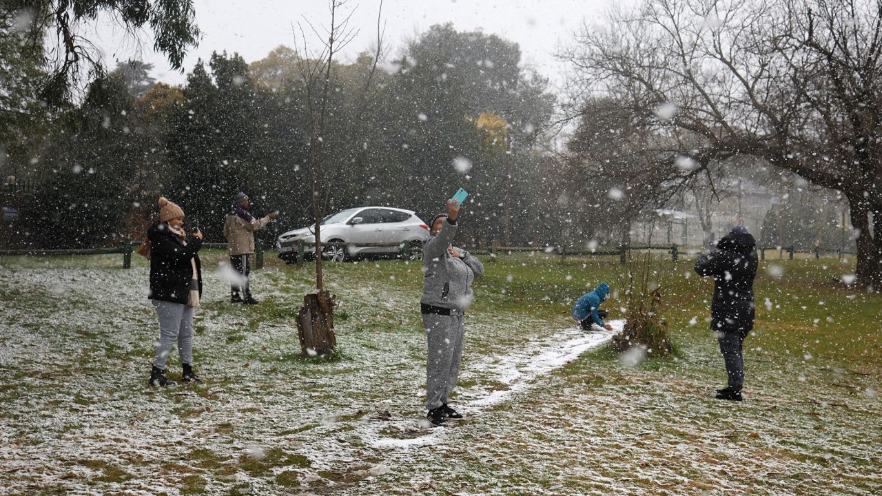 People take photos as snow falls in Zoo Lake park in Johannesburg on July 10.