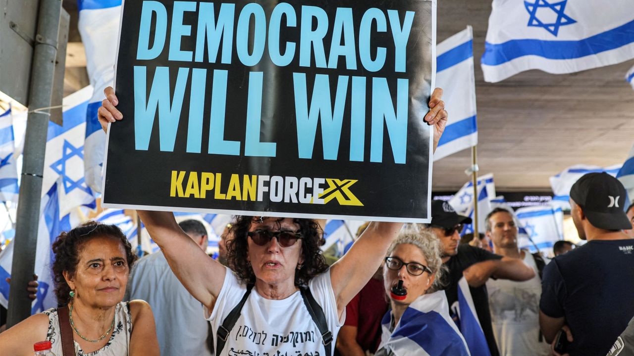 An anti-government demonstrator holds up a sign during a protest at Ben Gurion Airport near Lod on July 11, 2023. Protesters blocked roads across Israel on July 11 hours after parliament adopted in a first reading a key clause of the government's judicial overhaul package which opponents say threatens democracy. (Photo by JACK GUEZ / AFP) (Photo by JACK GUEZ/AFP via Getty Images)