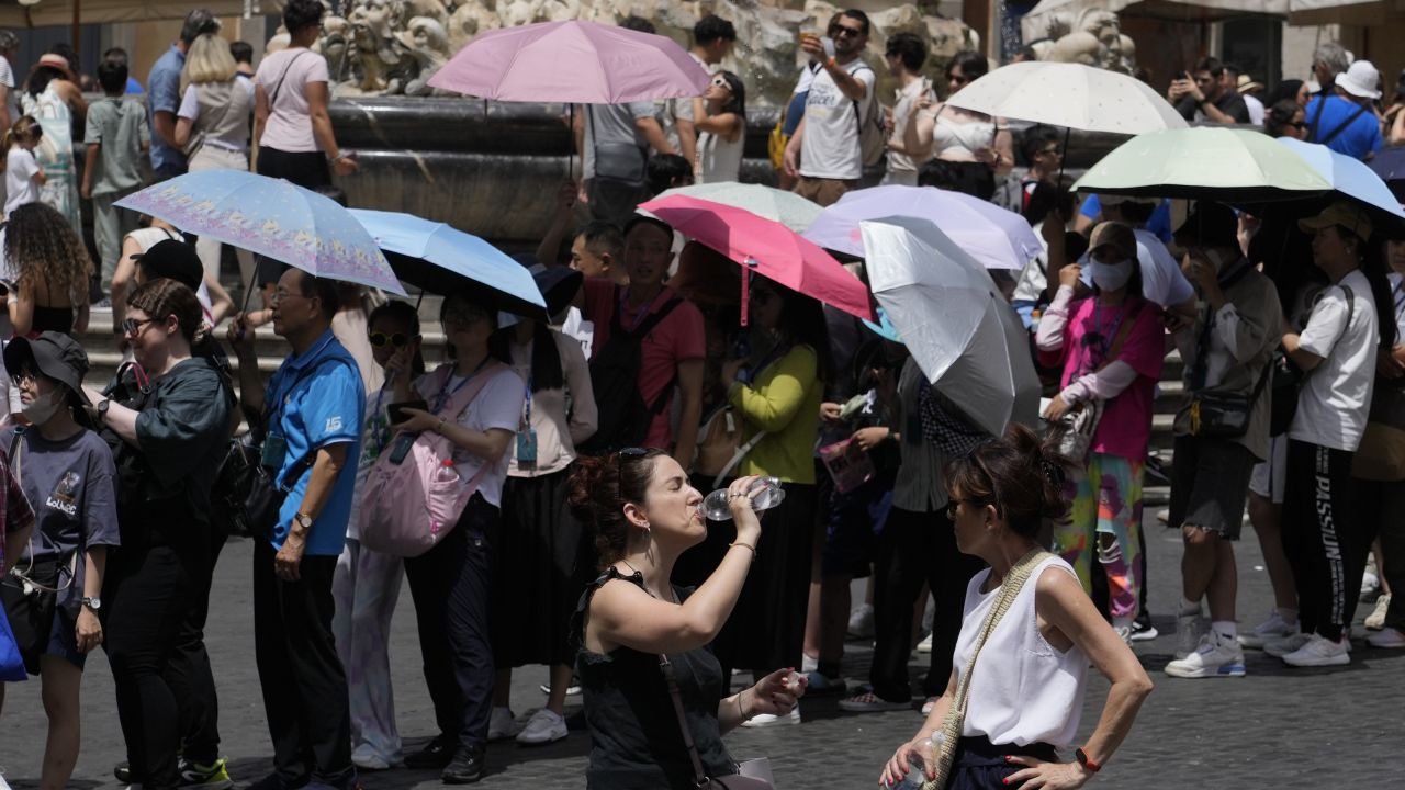 Los turistas usan sombrillas para protegerse del sol mientras hacen fila para ingresar al Panteón en Roma, el 8 de julio de 2023.