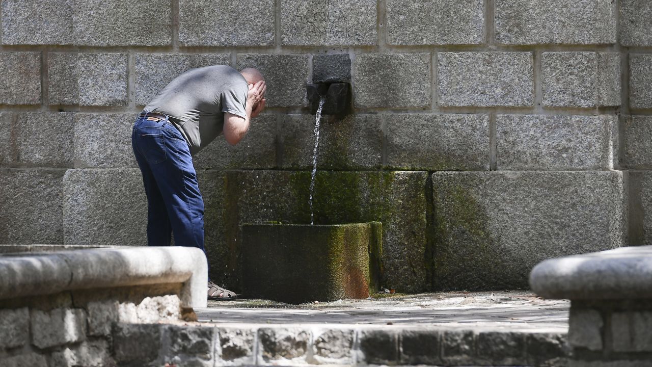 A man refreshes his face in a public fountain on July 11, 2023 in Tempio Pausania, Sardinia, Italy. 