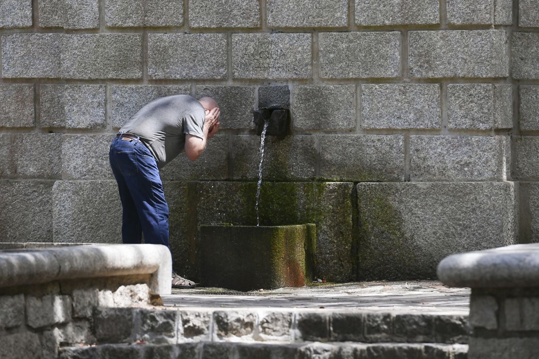 A man refreshes his face in a public fountain on July 11, 2023 in Tempio Pausania, Sardinia, Italy. 