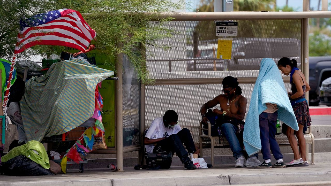 People gather under the shade of a Phoenix bus stop, Tuesday, July 11, 2023. Even desert residents accustomed to scorching summers are feeling the grip of an extreme heat wave smacking the Southwest this week.