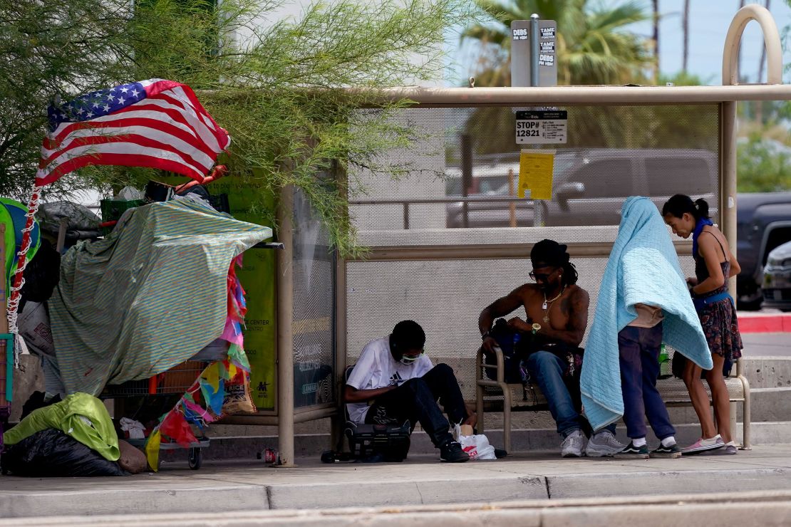 People gather under the shade of a Phoenix bus stop, Tuesday, July 11, 2023. Even desert residents accustomed to scorching summers are feeling the grip of an extreme heat wave smacking the Southwest this week. 