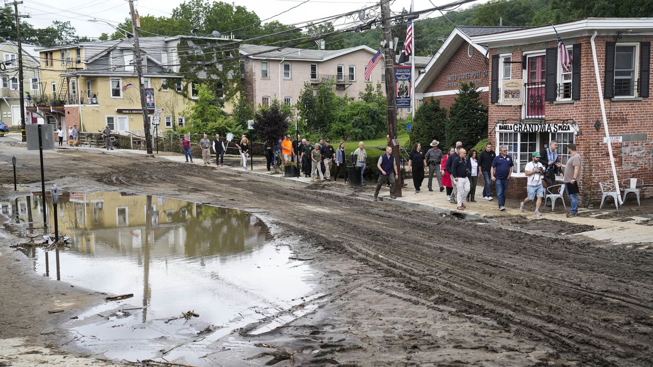 Governor Kathy Hochul and an entourage of emergency workers and journalists pass along Main Street, Monday, July 10, 2023, in Highland Falls, N.Y. Heavy rain has washed out roads and forced evacuations in the Northeast as more downpours were forecast throughout the day. One person in New York's Hudson Valley has drowned as she was trying to leave her home.