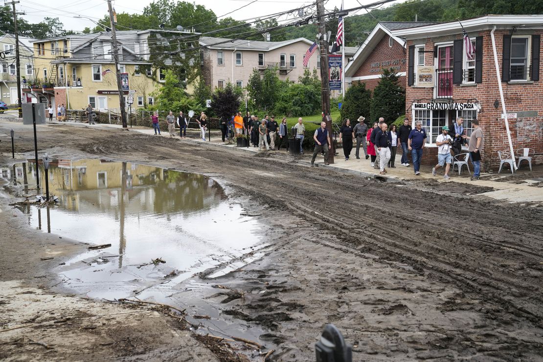 Governor Kathy Hochul and an entourage of emergency workers and journalists pass along Main Street, Monday, July 10, 2023, in Highland Falls, N.Y. Heavy rain has washed out roads and forced evacuations in the Northeast as more downpours were forecast throughout the day. One person in New York's Hudson Valley has drowned as she was trying to leave her home. 