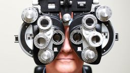 Mature man looking through Ophthalmic Instrument called a phoroptor.