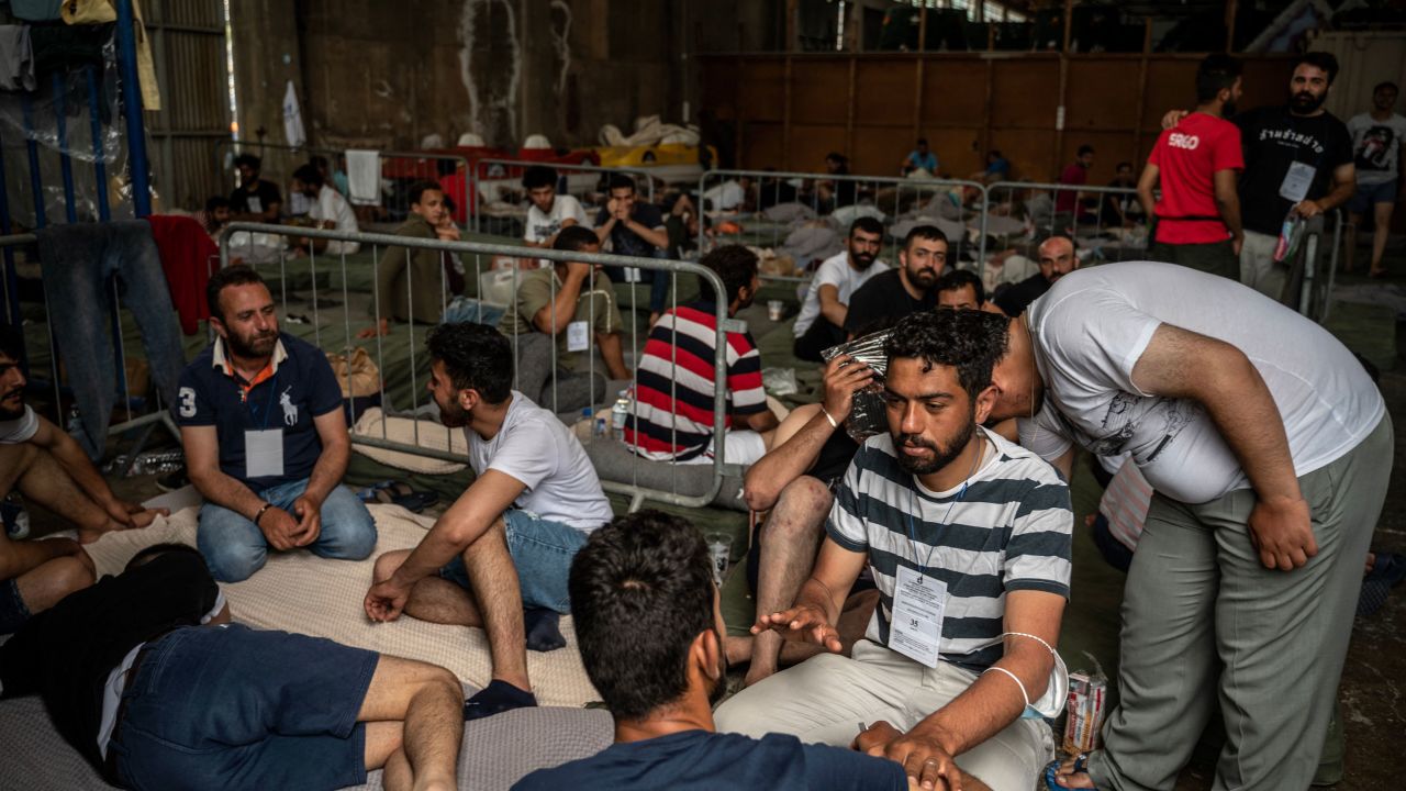 Survivors of the shipwreck sit inside a warehouse at the port in Kalamata town, on June 15.