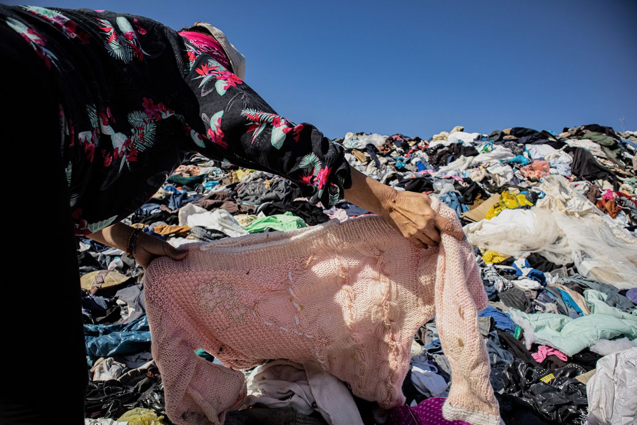 25 November 2021, Chile, Alto Hospicio: A woman searches for an item of clothing among a mountain of used clothes at a garbage dump. In the nearby free trade zone of Iquique, 29,178 tons of used clothing arrived in 2021 through October. About 50 importers sell the best pieces from them, while the others - estimated at 40 percent - sort them out.  (to dpa "Chile's Atacama Desert: Graveyard for Used Clothes") Photo: Antonio Cossio/dpa (Photo by Antonio Cossio/picture alliance via Getty Images)