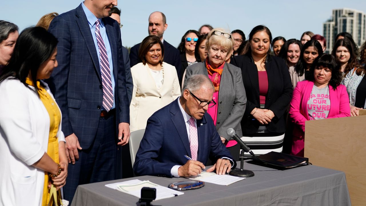 Washington Gov. Jay Inslee prepares to sign House Bill 1340, which protects healthcare providers in Washington from disciplinary action for providing legal abortion and gender-affirming care in Washington, as the bill's primary sponsor state Rep. Marcus Riccelli, D-Spokane, second from left, looks on, Thursday, April 27, 2023, at the University of Washington's Hans Rosling Center for Population Health in Seattle. (AP Photo/Lindsey Wasson)