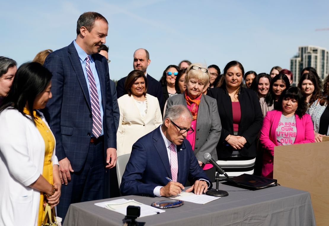 Washington Gov. Jay Inslee prepares to sign House Bill 1340, which protects healthcare providers in Washington from disciplinary action for providing legal abortion and gender-affirming care in Washington, as the bill's primary sponsor state Rep. Marcus Riccelli, D-Spokane, second from left, looks on, Thursday, April 27, 2023, at the University of Washington's Hans Rosling Center for Population Health in Seattle. (AP Photo/Lindsey Wasson)