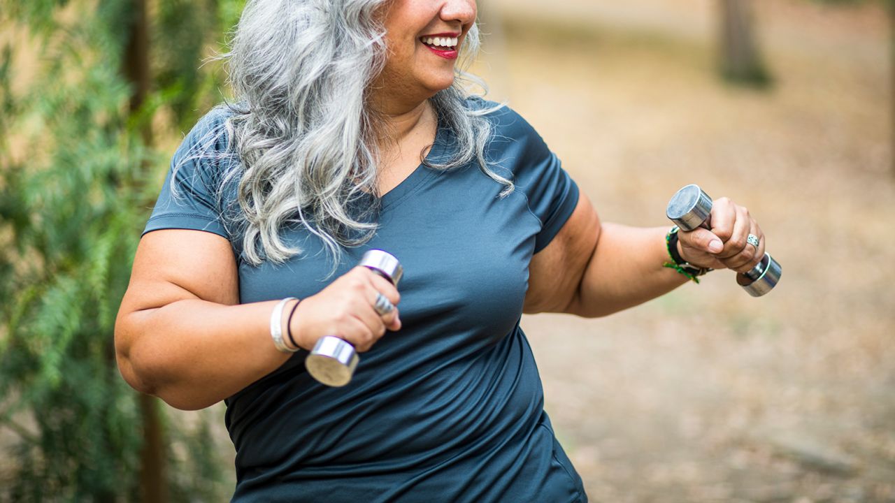 A beautiful senior Mexican Woman working out and stretching with weights