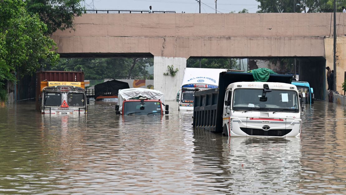 Trucks are seen partially submerged in a flooded street after the Yamuna River overflowed due to monsoon rains, in New Delhi on July 13, 2023.