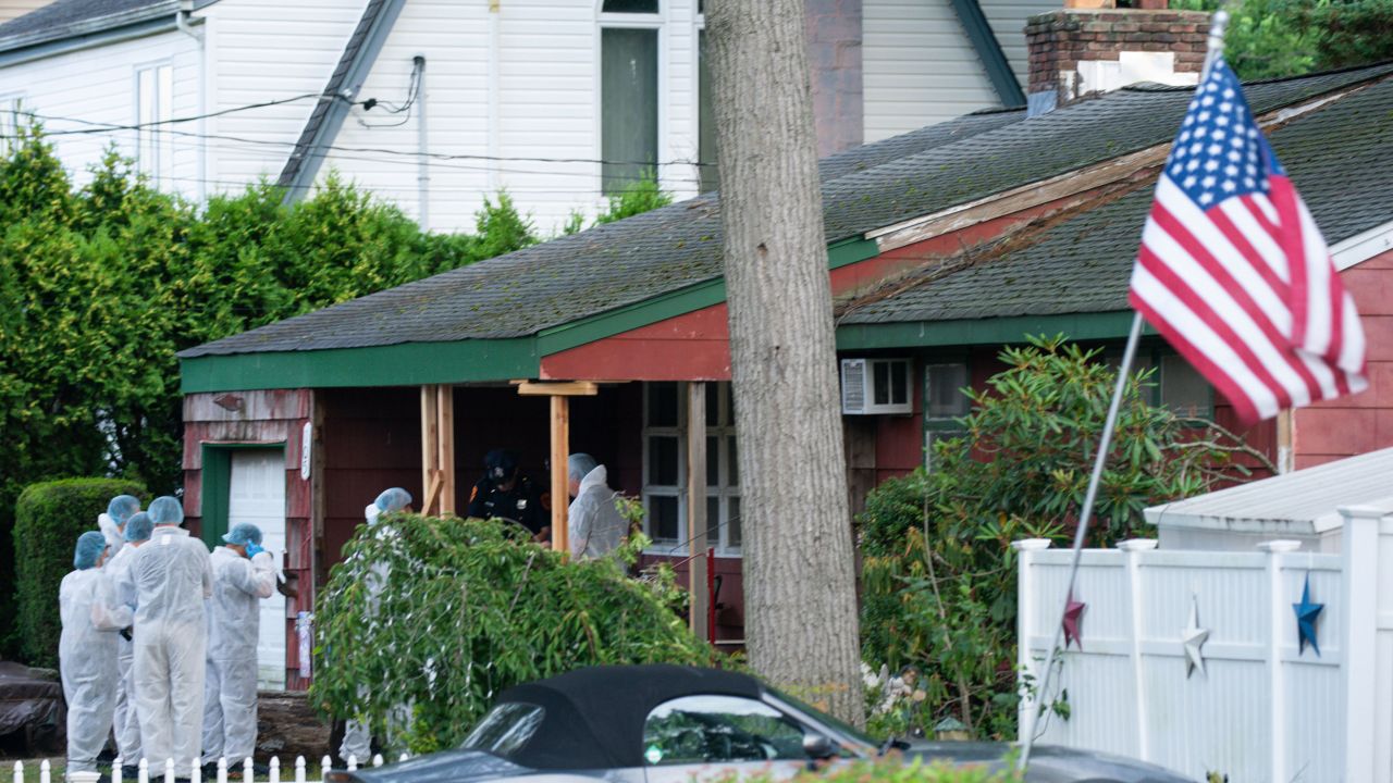 Crime laboratory officers arrive to a house Friday as sources said a suspect has been taken into custody in connection with a long-unsolved string of killings on New York's Long Island.