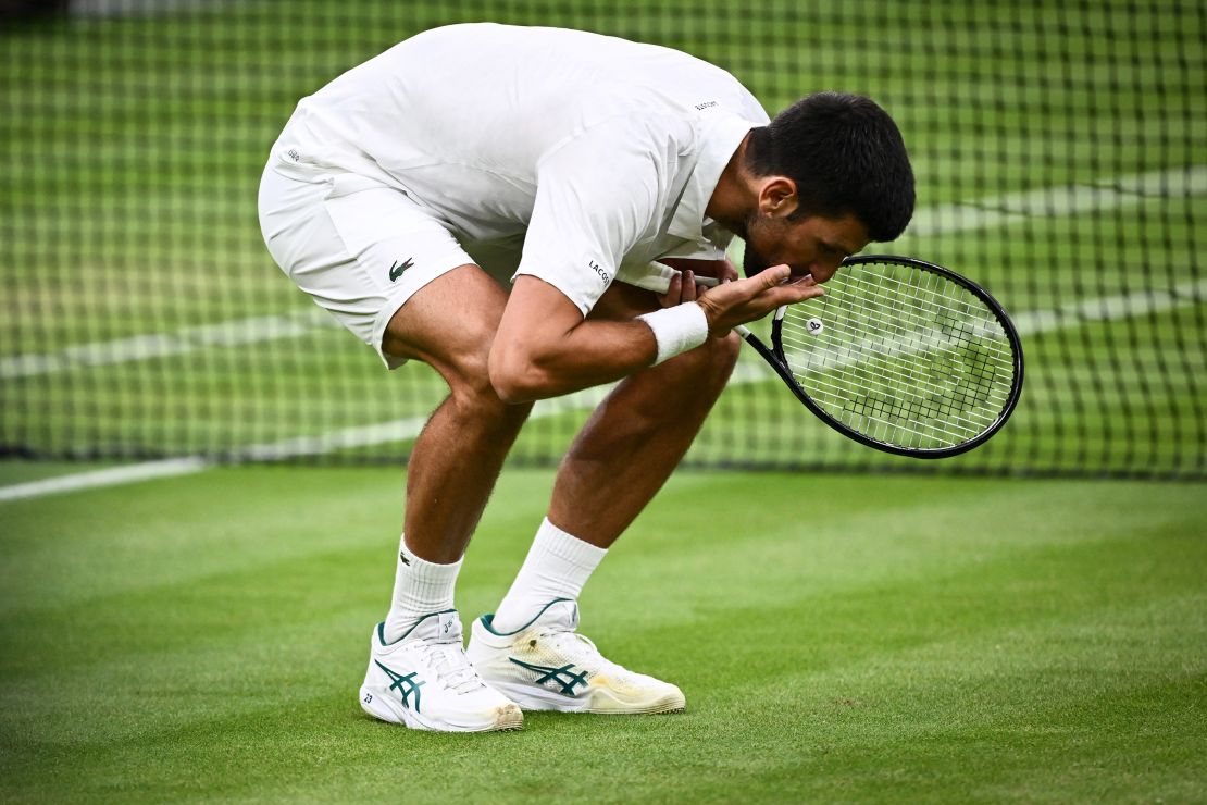 Novak Djokovic kisses the grass after beating Jannik Sinner.
