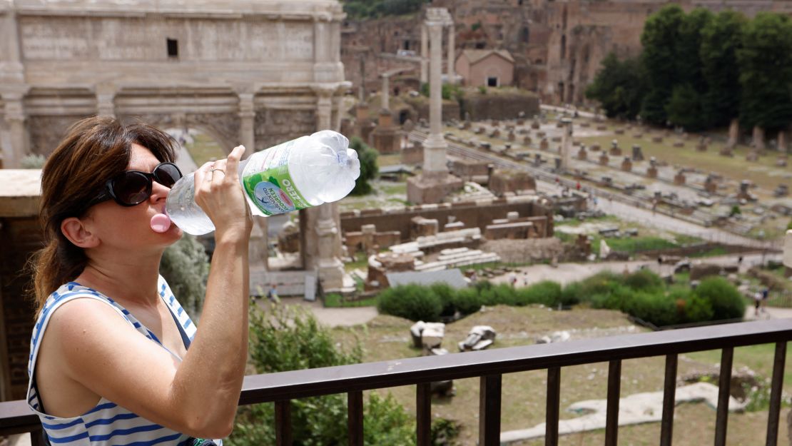 A woman in Rome drinks water near the Roman Forum.