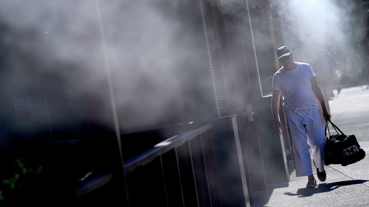 A man cools off under misters in Phoenix on Friday, where temperatures continued to top 110 degrees. 