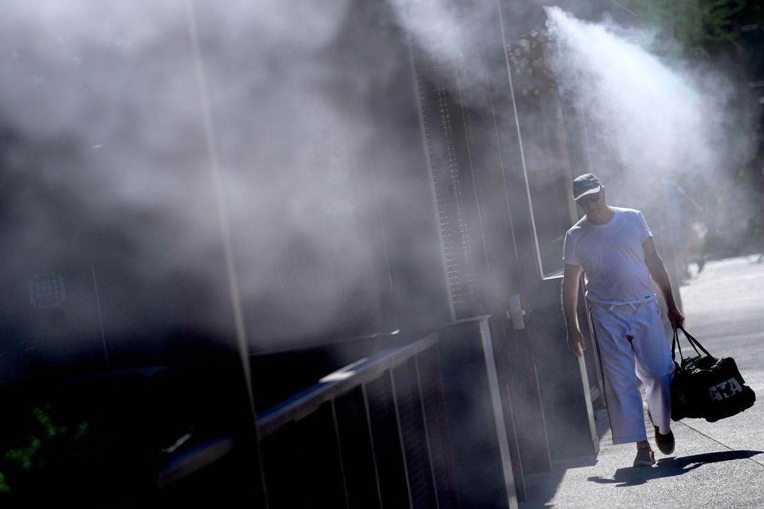 A man cools off under misters in Phoenix on Friday, where temperatures continued to top 110 degrees.