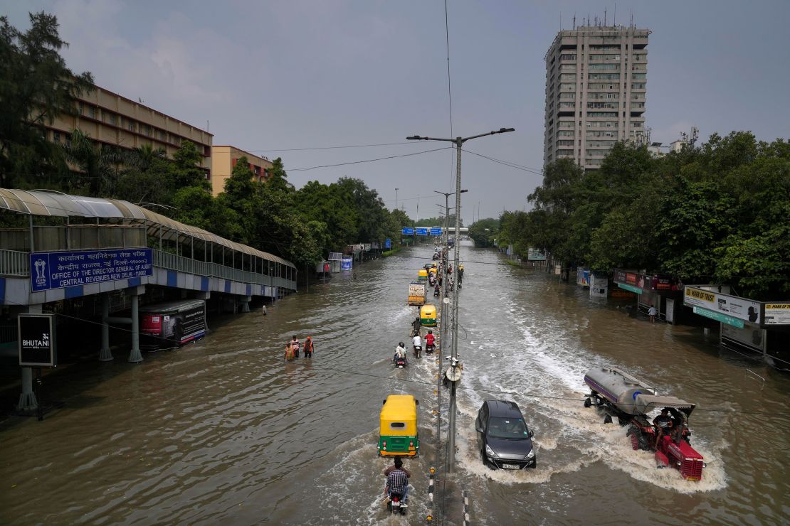 Commuters drive through a street inundated with floodwaters from the swollen river Yamuna, in New Delhi, India, Friday, July 14, 2023.