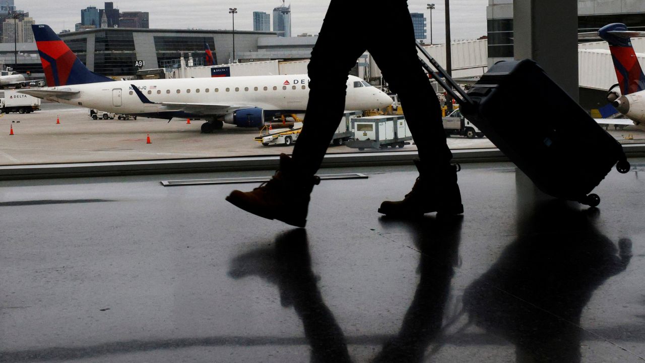 A passenger walks past a Delta Airlines plane at a gate at Logan International Airport in Boston, Massachusetts, U.S., January 3, 2022.  