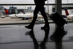 A passenger walks past a Delta Airlines plane at a gate at Logan International Airport in Boston, Massachusetts, U.S., January 3, 2022.  