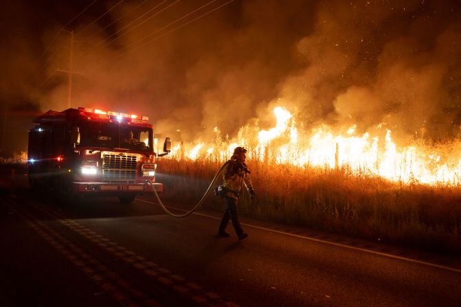 A firefighter watches flames from the <a href="index.php?page=&url=https%3A%2F%2Fwww.cnn.com%2F2023%2F07%2F16%2Fus%2Fcalifornia-wildfires-extreme-heat%2Findex.html" target="_blank">Rabbit Fire</a> approach Gilman Springs Road in Moreno Valley, California, on July 14.