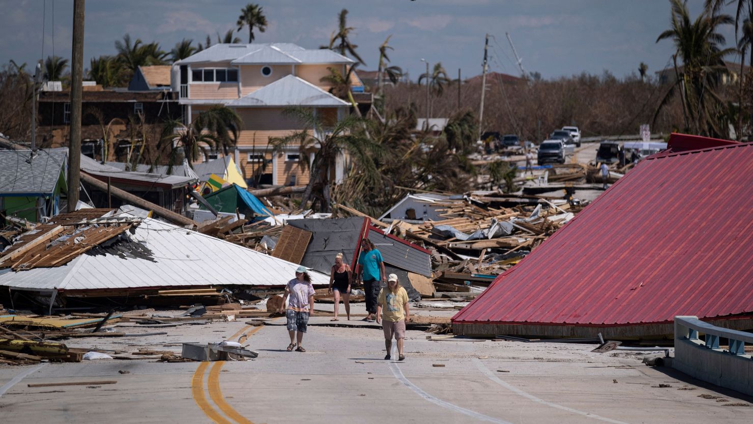 People walk pass destroyed houses and businesses in the aftermath of Hurricane Ian in Matlacha, Florida, on October 1, 2022.  