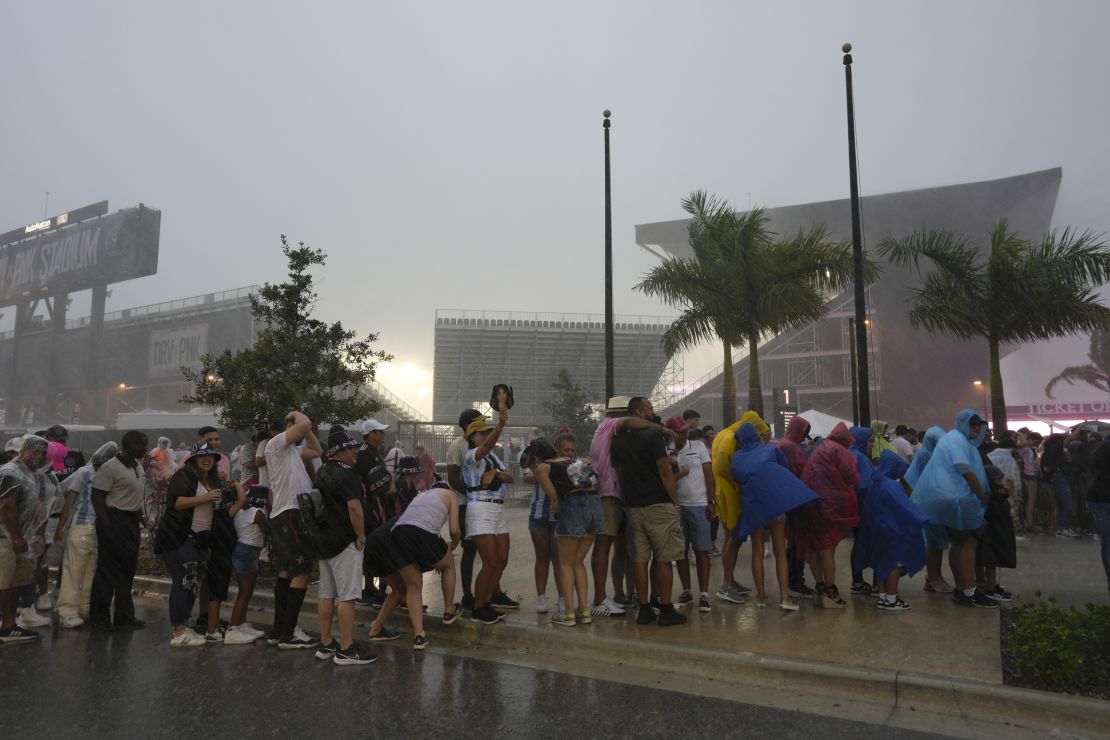 Fans wait in line in a downpour to enter DRV PNK Stadium, home of the Inter Miami MLS soccer team, for an event to present international superstar Lionel Messi one day after the team finalized his signing through the 2025 season, Sunday, July 16, 2023, in Fort Lauderdale, Fla. (AP Photo/Rebecca Blackwell)