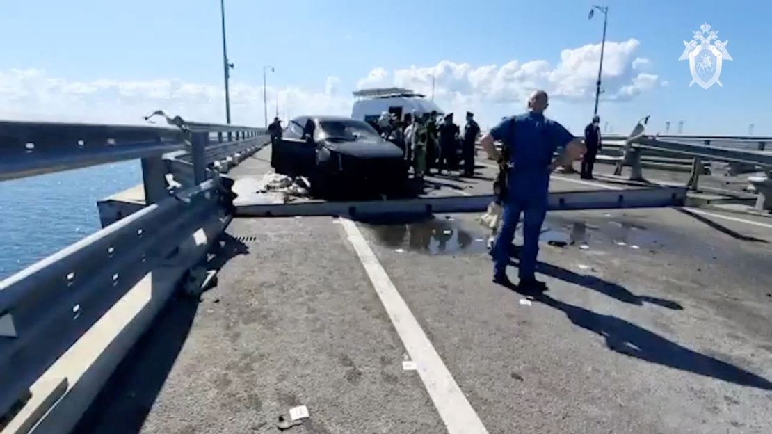 Russian investigators gather near a destroyed car at the damaged section of the bridge on July 17, 2023.
